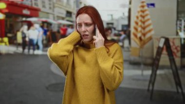 Sarı kazaklı bir kadın, şehir caddesinde telefonla konuşuyor. İnsanların ve kafelerin geçmişi bulanık, duyguları ve şehir yaşam tarzını tasvir ediyor..