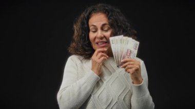 Tayvan banknotları tutan kadın, izole edilmiş siyah bir arkaplan karşısında şaşkınlık gösteriyor. Odaklanmış bir portrede finansal kazanç ve duygu temalarını vurguluyor..