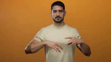 Genç İspanyol adam canlı turuncu arka plana karşı gözleri kapalı meditasyon yapıyor, dinginlik ve sükunet yayıyor..