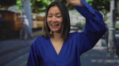 Mavi elbiseli genç bir kadın, şehir sokaklarında gülümserken gözlerini kapatıyor. Canlı enerji ve spontane duygularla dolu neşeli bir şehir sahnesi yaratıyor..