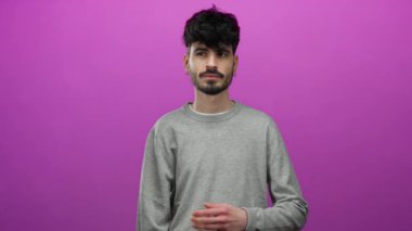 Gri kazaklı genç adam soyutlanmış pembe arka plana karşı duruyor. Samimi ve düşünceli görünüyor..