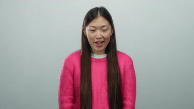 Beyaz arka planda gülümseyen pembe süveter giyen kadın Asya zarafetini ve cazibesini simgeleyen uzun saçlı güzellik ve sıcaklık yayar.