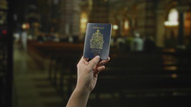Kilisede elinde Kanada pasaportu olan bir adam var. Arka planı bulanık. Kol ve kimlik belgelerini elinde tutuyor..