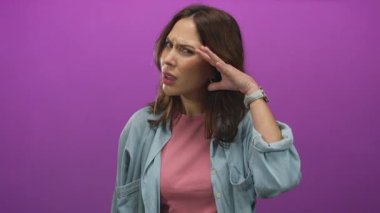 Kot giymiş bir kadın pembe arka planda şaşkınlık içinde kulağını tutuyor. Meraklı, soyutlanmış, hareketli, canlı, etnik bir kadın modeli olduğunu ifade ediyor. Duygularını yansıtıyor..