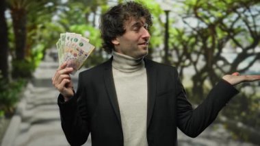 Bir şehir caddesinde gülümseyen ve elinde Arjantin pezosu tutan İspanyol bir adam, bir jest yapıyor, açık hava ortamında güven ve başarı sergiliyor.