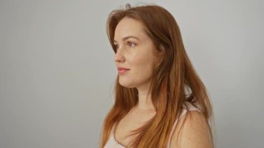 Beyaz arka planda sırıtan, uzun kızıl saçlı, doğal güzelliğini ve zarafetini gösteren bir kadın.