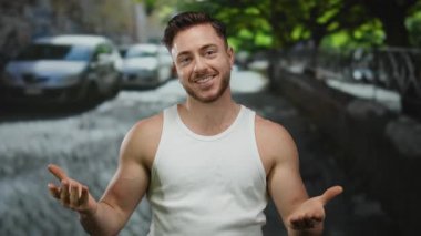 Sakallı genç adam yazın gülümseyen beyaz kolsuz tişörtlü şehir sokaklarında para dağıtıyor..