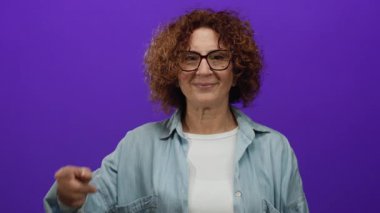 Kıvırcık esmer saçlı ve gözlüklü İspanyol kadın burnuna neşeli bir gülümseme ile bakıyor..