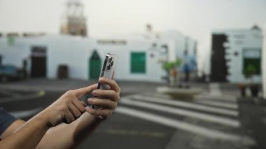 Şehir sokaklarında şehir geçmişi bulanık, akıllı telefon kullanan bir adam eller ve teknoloji etkileşimine odaklanıyor..
