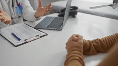 Klinikteki masada doküman ve dizüstü bilgisayarı olan bir doktora danışıyorum.