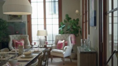 Şık yemek masası olan oturma odası, şık sandalyeler, büyük pencereler, yumuşak ışıklandırma, ve dekoratif bitkiler ev içinde rahat bir atmosfer yaratıyor..