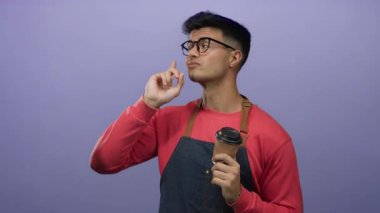 Gözlüklü genç adam ve önlüklü kırmızı kazak, kahve fincanı tutan, izole edilmiş mor arka plana kafa yoran