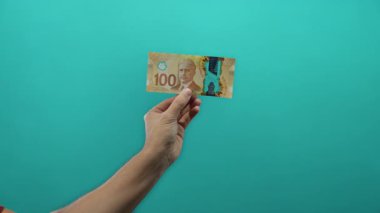 İzole edilmiş yeşil arkaplan duvarının üzerinde 100 dolarlık banknot tutan adam para birimi detaylarını açıkça gösteriyor..