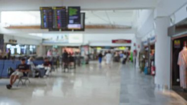 Yoğun havaalanı terminalinin bulanık arkaplanı çözülmüş gezginler, çıkış panoları ve dükkanlar bir bokeh etkisi yaratıyor.