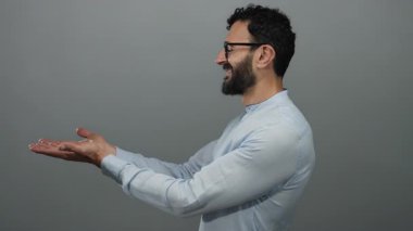 Gözlüklü, mavi gömlekli, gri arka planda gülümseyen İspanyol sakallı adam pozitifliğini ve açıklığını ifade ediyor..