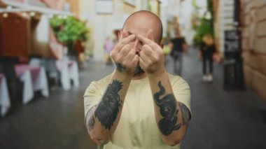 Dövmeli kel bir adam şehir sokaklarında kalp hareketi yapıyor neşeli bir havayı somutlaştırıyor ve canlı bir şehir ortamında rahat bir ortam yaratıyor..