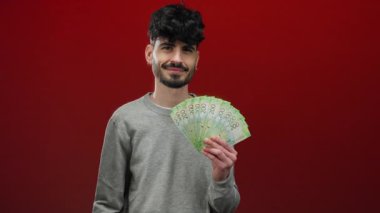 Elinde Rus rublesi banknotları tutan adam canlı kırmızı bir arka plana gülümsüyor zenginlik ve para gösteriyor..