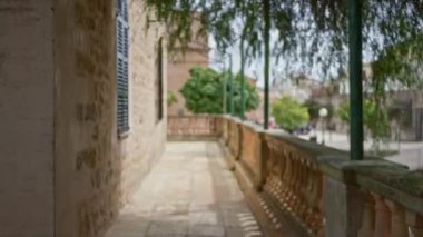 Yıpranmış balkonlu ve yemyeşil yapraklı tarihi taş bina, üniversite kampüsünde klasik mimarinin yer aldığı huzurlu bir manzara sunuyor..