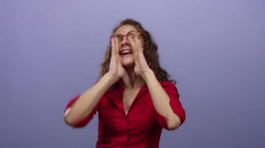 Kırmızı gömlek ve gözlük takmış, neşeli bir şekilde arka planda bağıran bir kadın heyecanlı bir ifadeyle coşku ve enerjiyi izole bir ortamda taşıyor..