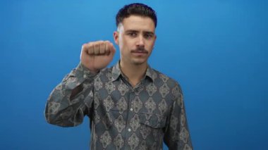 Genç İspanyol adam, izole edilmiş mavi arka plana karşı kapı çalma hareketi yapıyor. Merakını ve dikkatliliğini dile getiriyor..