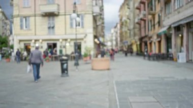 İtalyan caddesinde bulanık insanlar, renkli binalar ve La Spezia 'da canlı bir atmosfer var. Bokeh etkisine sahip canlı bir şehir manzarası yaratıyor..