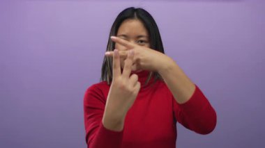 Kırmızı kazak giyen bir kadın, izole edilmiş mor arka plana karşı hashtag hareketi yaparak sosyal medya iletişimini öneriyor.