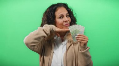 Orta yaşlı bir kadın, zenginlik ve memnuniyeti sembolize eden yeşil izole bir geçmişe karşı gülümsüyor ve elinde Romanya banknotları tutuyordu..