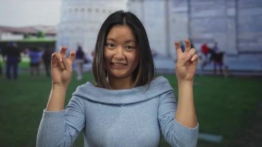 İtalya 'da Pisa Kulesi' nin önünde poz veren genç bir kadın neşeli bir ifadeyle barış işareti gösteriyor. Seyahat, kültür ve simgelerin özünü yakalıyor..