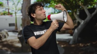 İspanyol bir adam açık havada megafonla gönüllü olarak güneşli bir sokakta motivasyon ve enerjisini ifade ediyor..