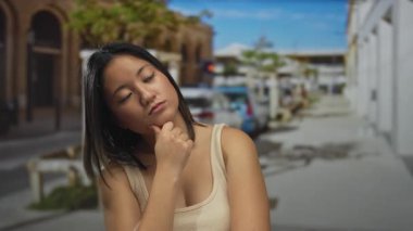 Güneşli bir günde şehrin arka planında bulanık gezen, düşünceli bir kadın..