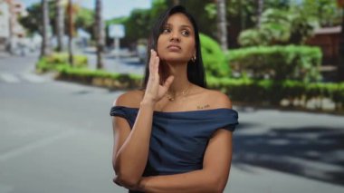 Genç İspanyol kadın, yemyeşil yemyeşil ve palmiye ağaçlarıyla güneşli bir sokakta sakin bir şehir ortamı yaratıyor..