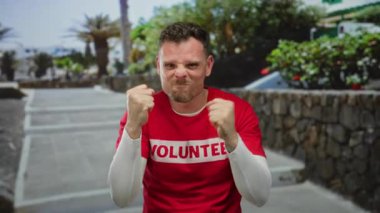 Açık hava ortamında duygularını ifade eden bir adam gönüllü gömleği giyip güneşli bir ortamda azim ve odaklanma gösteriyor.