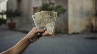 Bir şehir sokak ortamında Danimarka kronunun el ele tutuşması bir adamın şehir ortamında para idare etme hareketini yakalar..