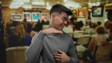 Bir sanat galerisinde arka planda canlı sanat eserleriyle gülümseyen yakışıklı bir adam..