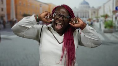 Kentsel atmosfer ve tarihi mimari ile çevrili, Vatikan 'daki St. Peter Meydanı' nda enerjik bir ifadeyle elleri kulaklarında bağıran bir kadın..