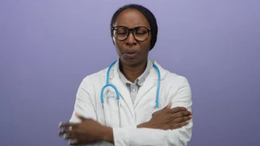 Steteskoplu kadın doktor, mor arka planda duran, profesyonel bir tavır sergiliyor..