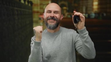 Kafkasyalı bir adam kilisede arabanın anahtarlarını tutarken mutluluğu ve zaferi neşeli bir ifadeyle ifade ederek kutluyor..