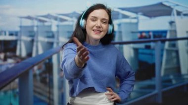 Bir yolcu gemisinin güvertesinde kulaklıkları ve neşeli bir ifadeyle rahat bir atmosfer ve canlı bir çevre sergileyen bir kadın..