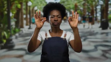 Şehir caddesinde bulanık yayalar ve canlı yeşilliklerle meditasyon yapan bir kadın..