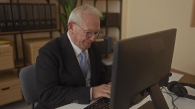 Takım elbiseli son sınıf öğrencisi, ofisteki bilgisayarda onaylıyor. Profesyonel iş ortamında güven ve memnuniyet gösteriyor..