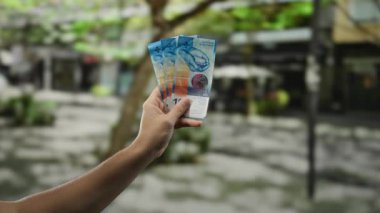 Bir şehir caddesinde İsviçre banknotları tutan adam, bulanık kentsel arka plan sergilenen mali konsept karşısında odak İsviçre franklarını yakalıyor.
