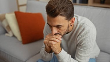 Evinde derin düşüncelere dalmış genç İspanyol bir adam yumuşak yastıklarla çevrili rahat bir oturma odasında dalgın dalgın oturuyor..