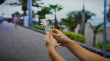 Endonezya rupia banknotlarını sayan adam hareketli bir şehir caddesinde, canlı bir şehir ortamında iş ve para değişimi sergiliyor..