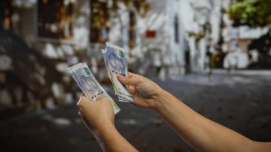 Güney Afrika Rand banknotlarını elinde tutan adam bir şehir merkezinde döviz değişimi sergiliyor, açık alandaki finansal anlaşmaları vurguluyor..