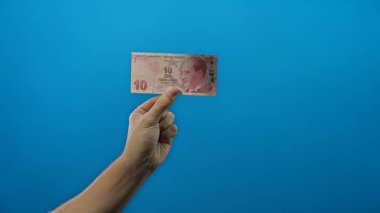 İzole edilmiş mavi arka planda Türk lira banknotu tutan adam, mali kavramları ve ekonomiyi Türkiye 'de temsil ediyor..