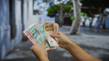 Şehir merkezindeki bir caddede Çin Yuan 'ı elinde tutan bir adam iş bağlamında para yönetimini sergiliyor..