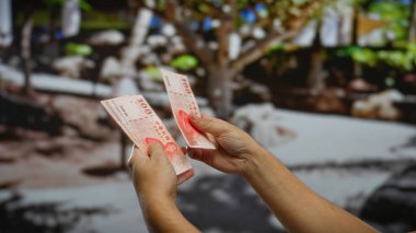 Kentsel bir sokakta Tayvan doları tutan eller, açık şehir ortamında iş yatırımlarını ve mali işlemleri sembolize ediyor..