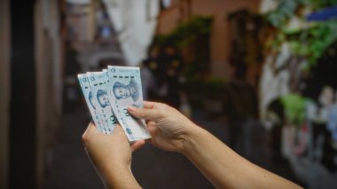 Şehir ortamında Çin Yuan banknotları tutan adam, hareketli bir şehir ortamında döviz değişimi sergiliyor..