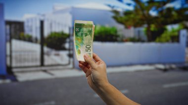 El ele tutuşan İsrail şekelleri bir şehir caddesinde belirgin bir şekilde sergileniyor, hareketli bir şehir ortamında mali değişim ve yatırım sahnesini yakalıyor.