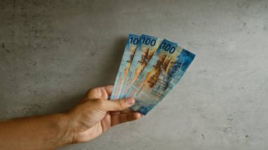 Beton bir duvarın önünde el ele tutuşan İsviçre frangı tarafsız bir endüstriyel ortamda İsviçre parası vurguluyor..